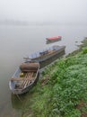 Foggy and gloomy autumn scene of boats moored along riverbank. Royalty Free Stock Photo