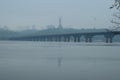 Foggy landscape view of famous Paton Bridge over Dnipro River. Blurred silhouette statue of Mother Fatherland