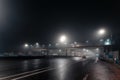 Foggy misty night road and overhead pedestrian bridge illuminated by street lights Royalty Free Stock Photo