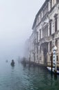 Foggy (misty) Venice. Canal, historical, houses and gondoliers with gondolas on thick fog. Royalty Free Stock Photo