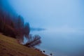 Foggy morning on the border of calm lake in Austrian Alps
