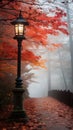 On a foggy morning, stands an old tall high lantern post amidst a sea of fallen leaves. Royalty Free Stock Photo