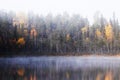 A foggy morning in the colorful taiga forest by a small lake during autumn foliage colors Royalty Free Stock Photo