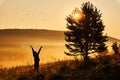 Foggy morning in the hills. The silhouette of a girl happily tossing flowers in the air. Beautiful golden sunrise