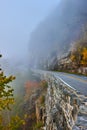 Foggy morning on road through cliffs next to stone block wall Royalty Free Stock Photo