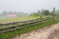 A road with a wooden fence, lonely house in the fog Royalty Free Stock Photo