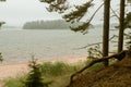 Foggy morning by the sea. Sandy coast, pine forest. the island is visible in the distance. The nature of Scandinavia. Finland. Por Royalty Free Stock Photo