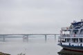 Foggy river cruise tourist ships, bridges across the lake, thick clouds low over Royalty Free Stock Photo