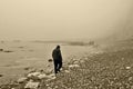 A foggy sea scene, A man walking along the sea edge on a very foggy day.