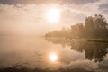 Foggy sunset with forest at long coast line, golden calm lake, Swedish countryside