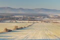 Foggy winter landscape with agricultural field and views of the village of Suha Reka