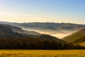 Foggy winter morning sunrise over a rural hilly idyllic landscape with fields, forest, fog in the valleys Royalty Free Stock Photo