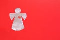 Foil-cut angel figurine on a red background. Place for text about Valentine's Day, love, religion or Angel Day holiday