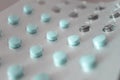 Foil packet of little round pills. Close-up blue medicine tablets packed in blister with selective focus. Macro drugs