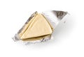 Foil wrapped processed creame cheese slice isolated on a white background. Small triangular piece of portioned soft cheese in a