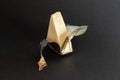 Foil wrapped processed creame cheese slice on a black background. Small triangular piece of portioned soft cheese in a