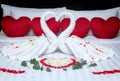 Fold a towel swan for decorations with rose petals on bed.