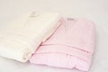 Folded bathrobe on bed in room. White and pink, two robes Royalty Free Stock Photo