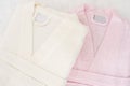 Folded bathrobe on bed in room. White and pink, two robes Royalty Free Stock Photo