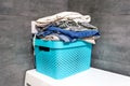 Folded bedding, jeans, towels on a blue box against the blurred background of a gray concrete wall in the bathroom Royalty Free Stock Photo