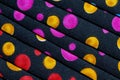 Folded fabric with red, blue, pink, gold and green dots / circles