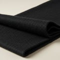 Folded black fabric, possibly wool or a similar material, displayed on a light surface. The Royalty Free Stock Photo