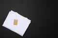 Folded blank white t-shirt with tag on black background Royalty Free Stock Photo