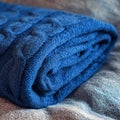 A folded blue knitted blanket on a textured grey surface cloth Royalty Free Stock Photo