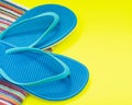 Folded Colorful Striped Organic Cotton Beach Towels and Blue Flip Flops on bright yellow
