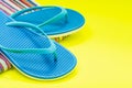 Folded Colorful Striped Organic Cotton Beach Towels and Blue Flip Flops on bright yellow Royalty Free Stock Photo