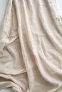 Beige fabric texture close-up. Folded curtain or sheet reveals intricate patterns and depth. Smooth surface with natural canvas