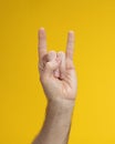 Folded fingers in shape of goat with two fingers raised up of man hand on yellow background Royalty Free Stock Photo