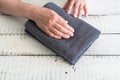 Folded grey towel on a white wooden table near woman`s hands. Spa and wellness, cotton terry textile. Ecological theme. Royalty Free Stock Photo