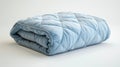 Folded light blue quilt on white background, studio shot. Bedding and textile concept. Royalty Free Stock Photo