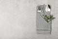 Folded napkin with fork, spoon and knife on grey background, top view Royalty Free Stock Photo