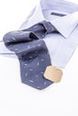 Folded new shirt and dark blue necktie with blank label on white Royalty Free Stock Photo