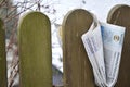 Folded newspaper clamped between pickets of a wooden fence