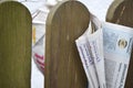 Folded newspaper clamped between pickets of a wooden fence