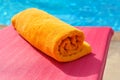 Folded orange towel on the background of the pool