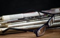 Folded pile newspapers with a pair of blue reading glasses on it