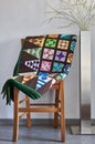 Folded quilt on a chair and floor lamp against a neutral wall