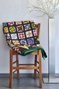 Folded quilt on a chair and floor lamp against a neutral wall