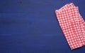 Folded red and white cotton kitchen napkin on a wooden blue background, top view Royalty Free Stock Photo