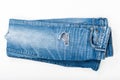 Folded ripped blue jeans on white background. Top view. Fashion