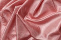 Folded shiny wrinkled satin of pale coral pink color texture. Background of draped powder pink silk cloth. Elegant luxury silky