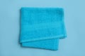 Folded soft beach towel on light blue background, top view