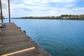 A folded spiral mooring rope with a end knot around a cleat on a wooden pier Royalty Free Stock Photo