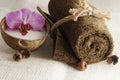 A folded towel, tied with a rope and an orchid flower in milk in a coconut on a light woven napkin, preparation for the spa proced Royalty Free Stock Photo