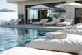 Folded towels on a poolside sunbed with a serene pool and lounge area