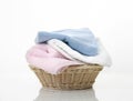 Folded towels stack in basket on white background,heap of colorful laundry on table Royalty Free Stock Photo